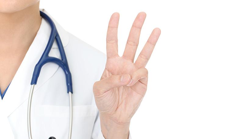 3つの数を示す女性医師の手