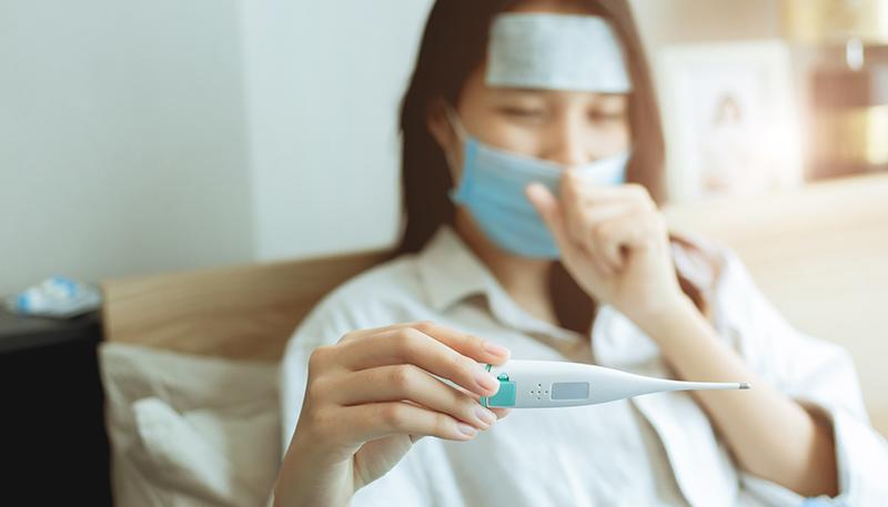 Asian women looking body temperature at oral thermometer for diagnosing flu from Coronavirus (Covid-19) infection self care stay at home.