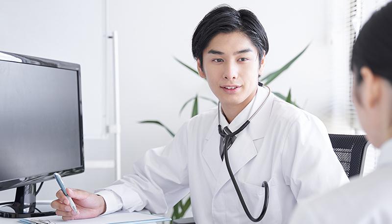 女性会社員を診察する日本人男性ドクター