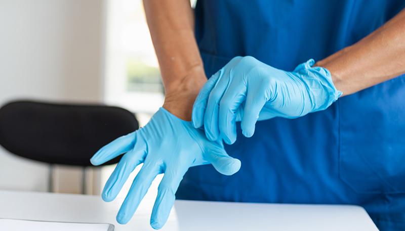 doctor is wearing blue rubber gloves prevent direct contact with patient because virus may be traced to patient body and medical rubber gloves also help prevent virus from being transmitted to patient