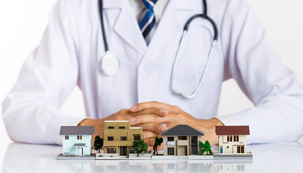 コミュニティホスピタルで働く医師のイメージ_住宅模型と白衣を着た医師